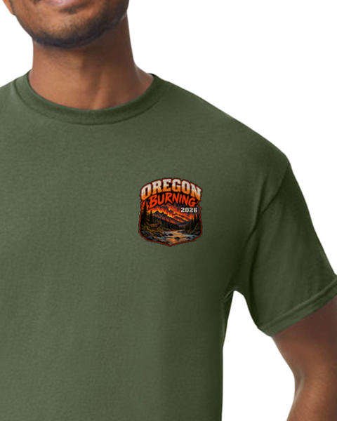A man wearing an olive green crewneck t-shirt with a 'OREGON BURNING 2026' graphic printed on the left chest.