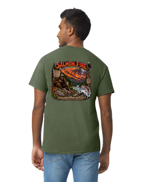 A man wearing an olive green t-shirt with a large, colorful graphic on the back depicting a salmon creek scene with the text 'SALMON FIRE' & 'BLUE MOUNTAINS 2026'